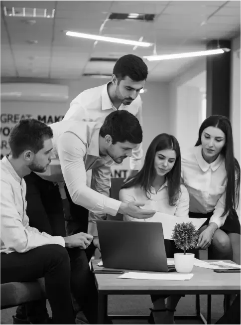A team reviewing work together around a laptop